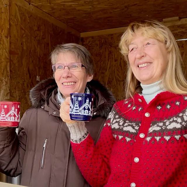 Zwei Frauen im Getränkestand mit jeweils einer Glühweintasse in der Hand