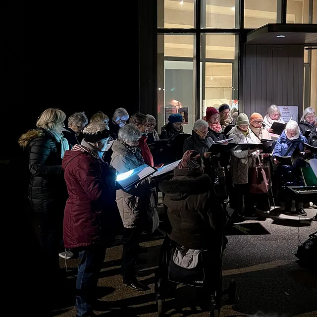 Ein Frauenchor bei Dunkelheit vor dem Eingang der Immanuel-Kirche